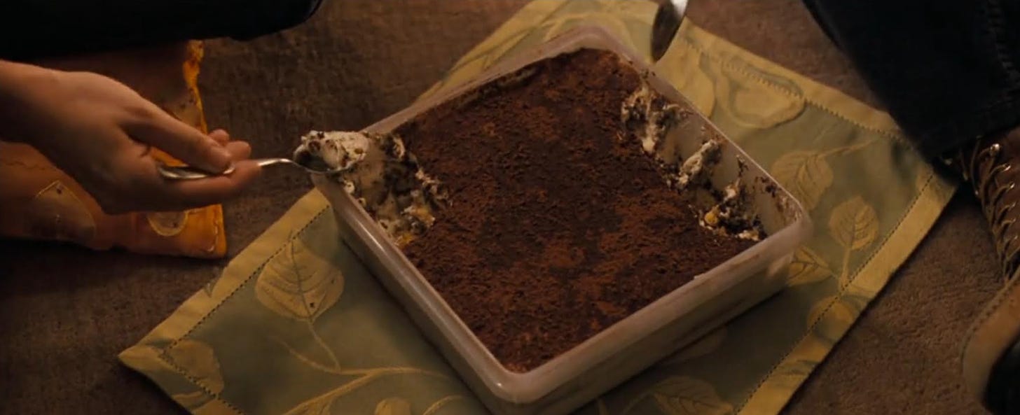 Movie still from No Reservations. A hand takes a spoonful of tiramisu from a tray.