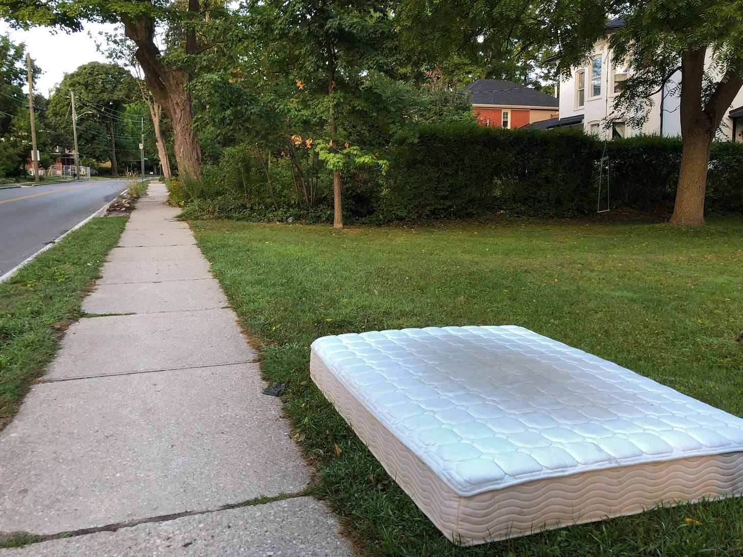 A mattress lies abandoned on grass by the side of a road the first spring of pandemic. Photo credit: Nancy Forde. All right reserved. nancyforde.com