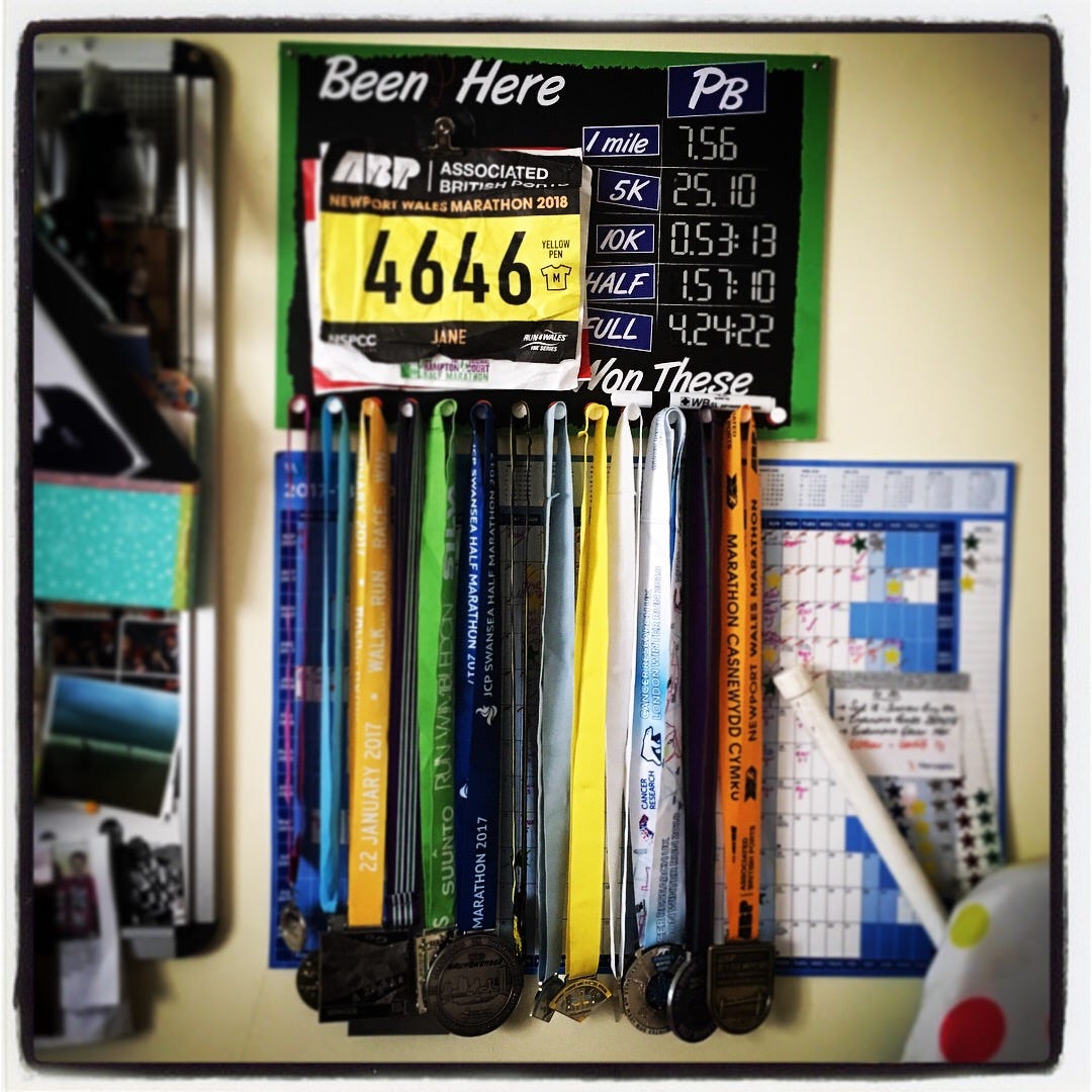 An image of multiple running medals and PBs on a board