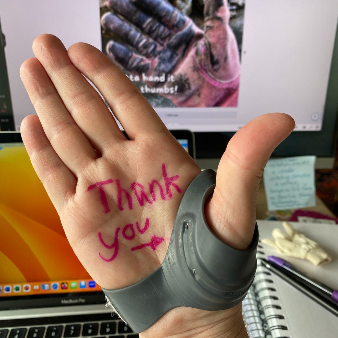 Author's hand with a thumb brace and on the palm in pink ink it says Thank you with an arrow pointing to the thumb.