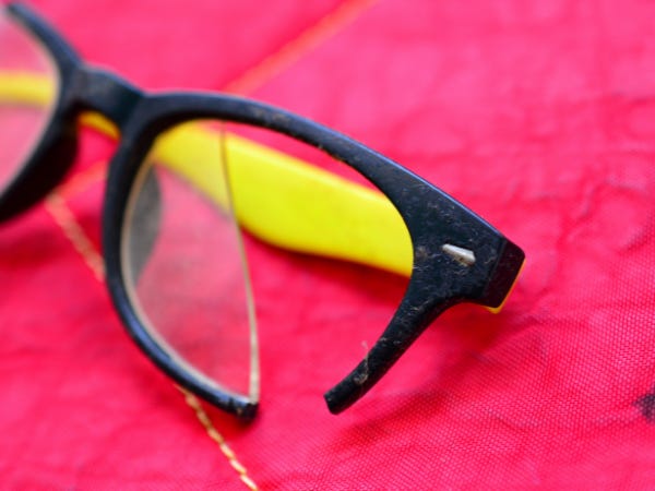 Broken lenses in black and yellow frames against a bright pink background