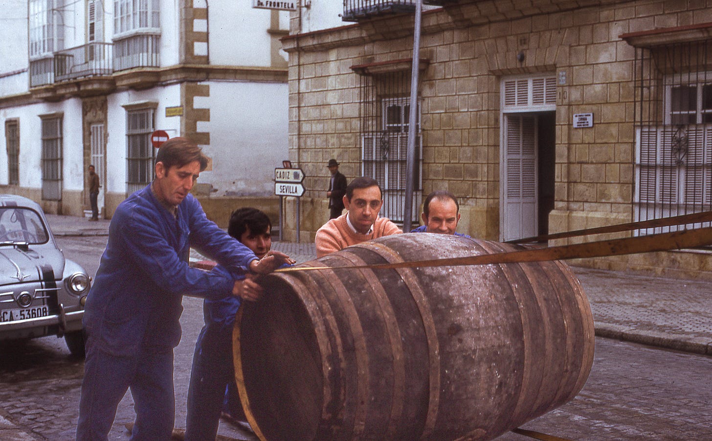 Four men loading a barrel on a truck