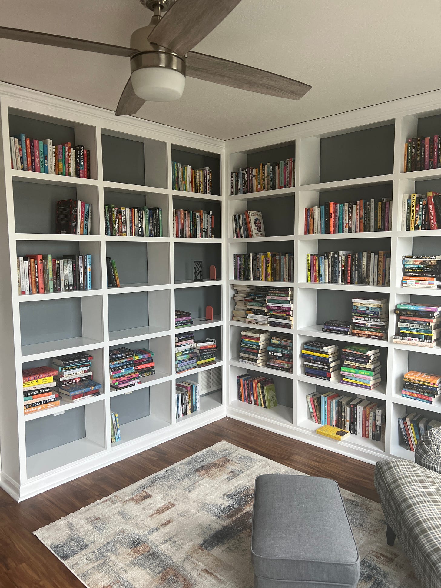 White built-in bookshelves with hundreds of books stacked haphazardly.