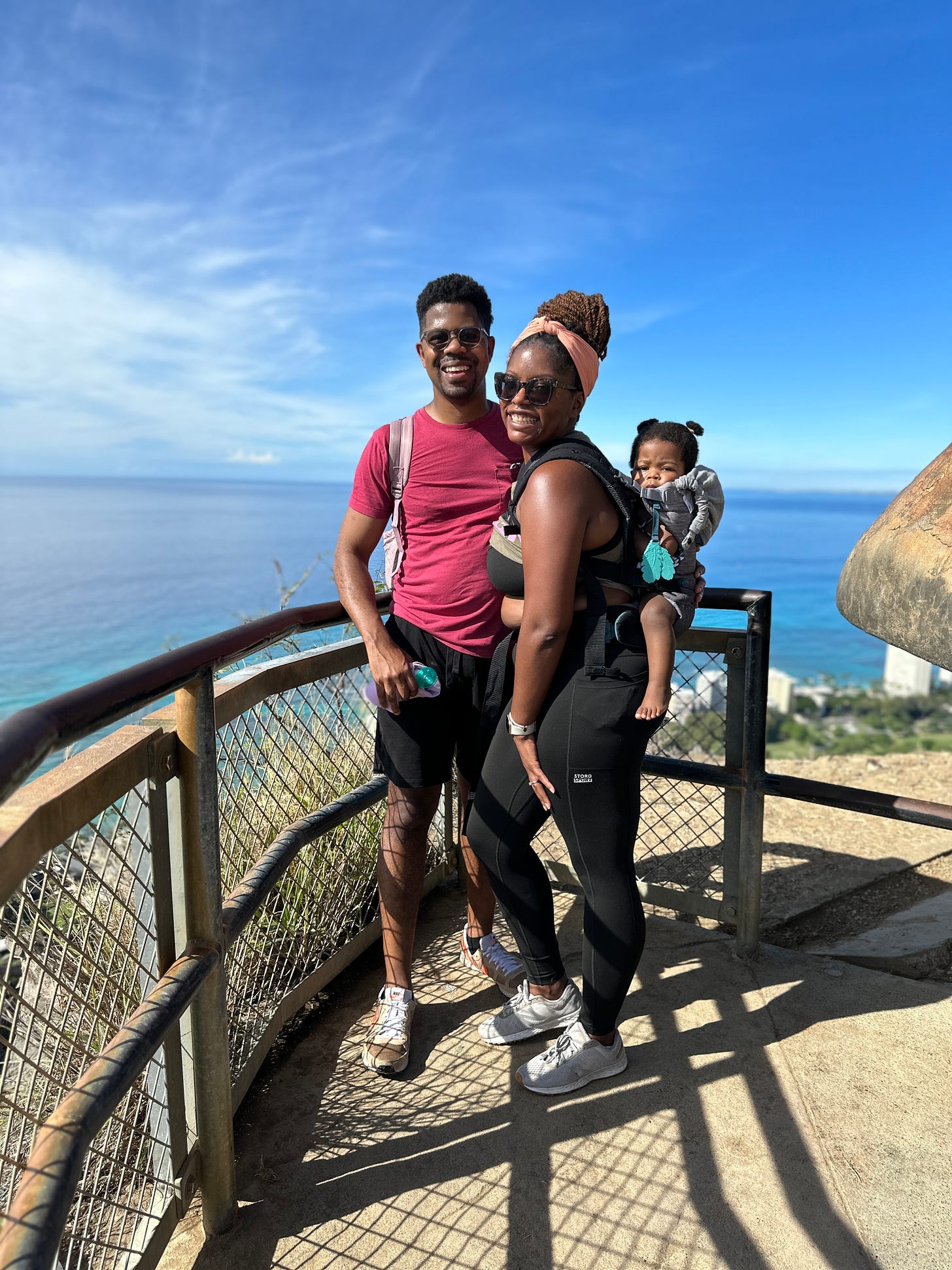 Black family posing during hike at landing spot overlooking the Pacific Ocean.