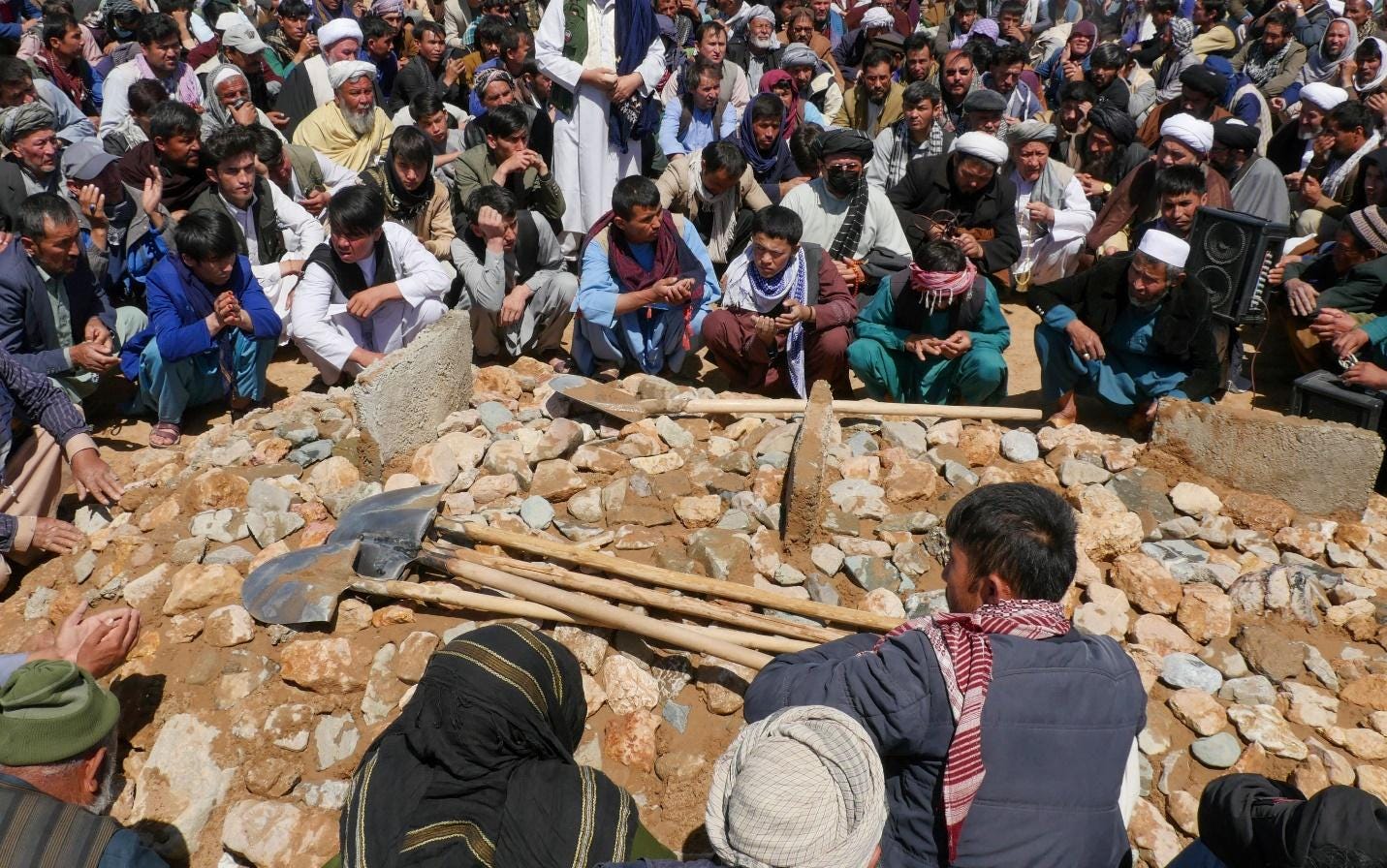 A crowd surrounds a burial site