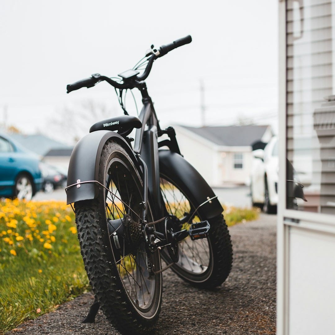 a black bike parked on the side of a road a black bike parked on the side of a road