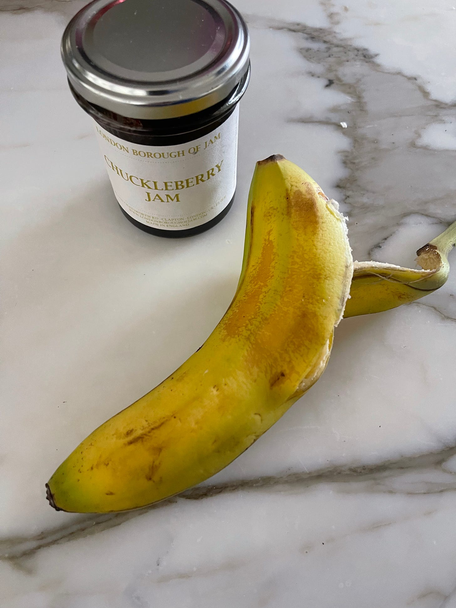 a half eaten banana sitting alongside a jar of jam
