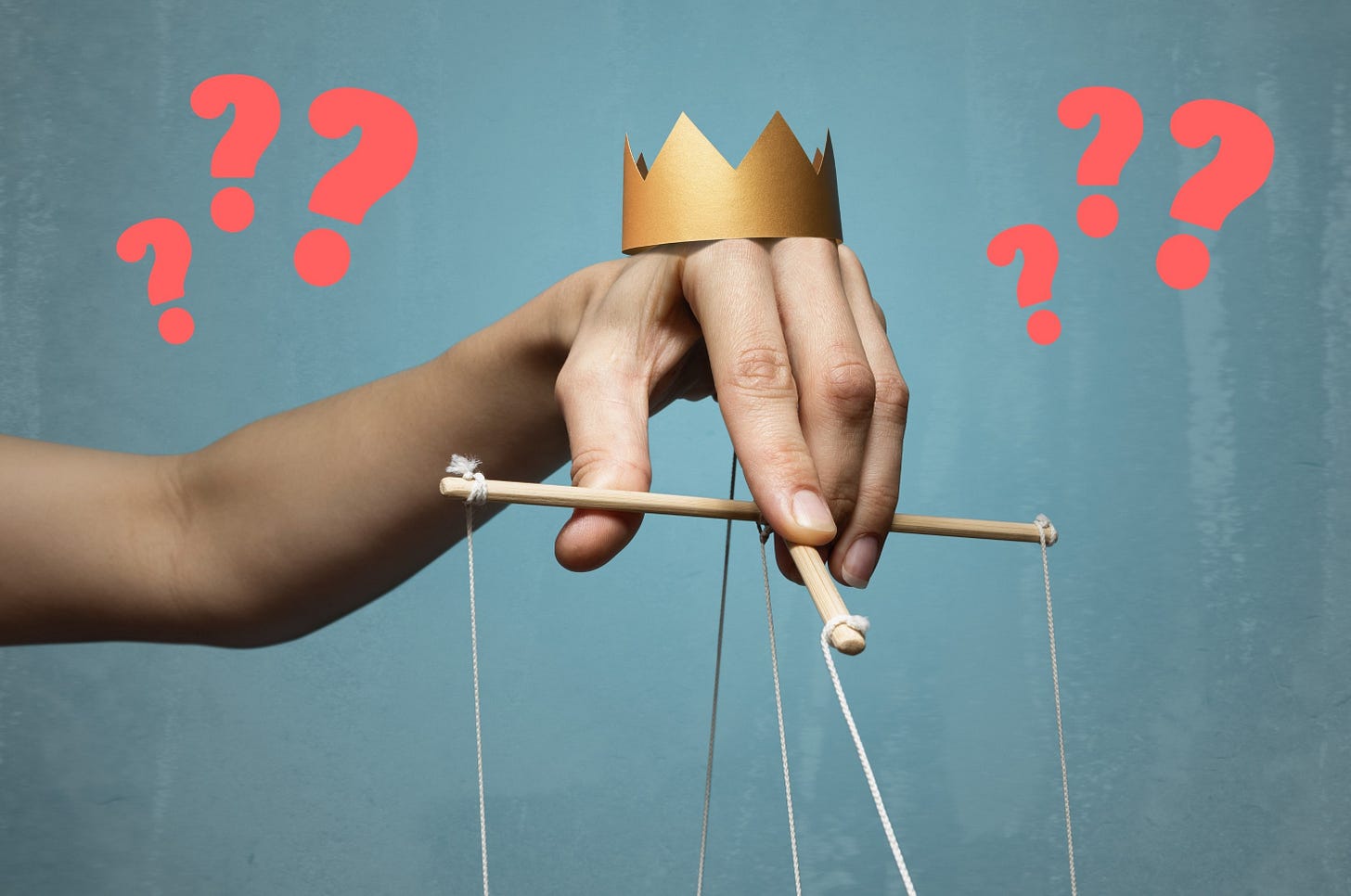 Hand with crown on it and holding puppet strings with question marks to either side.