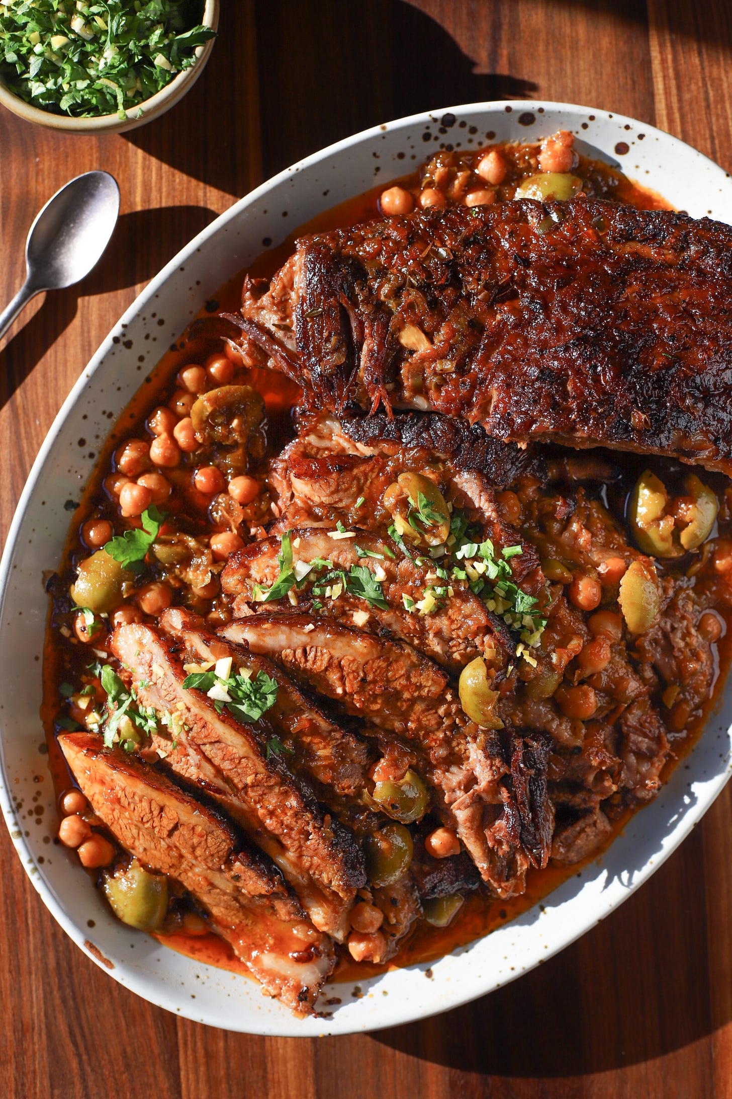 Platter with sliced brisket in a sauce of wine-braised chickpeas and olives