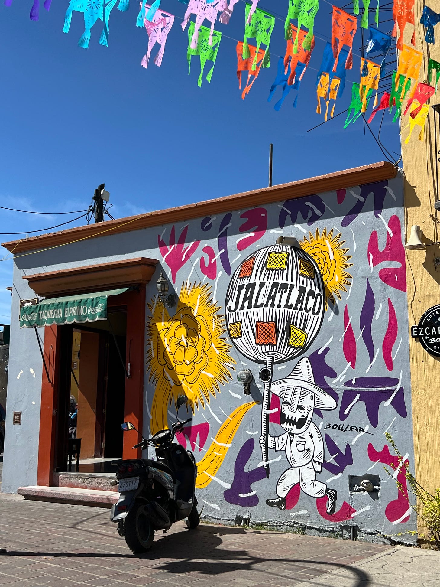 A mural covering a wall featuring an image of a skeleton man carrying a large ball labeled with the name Jalatlaco.