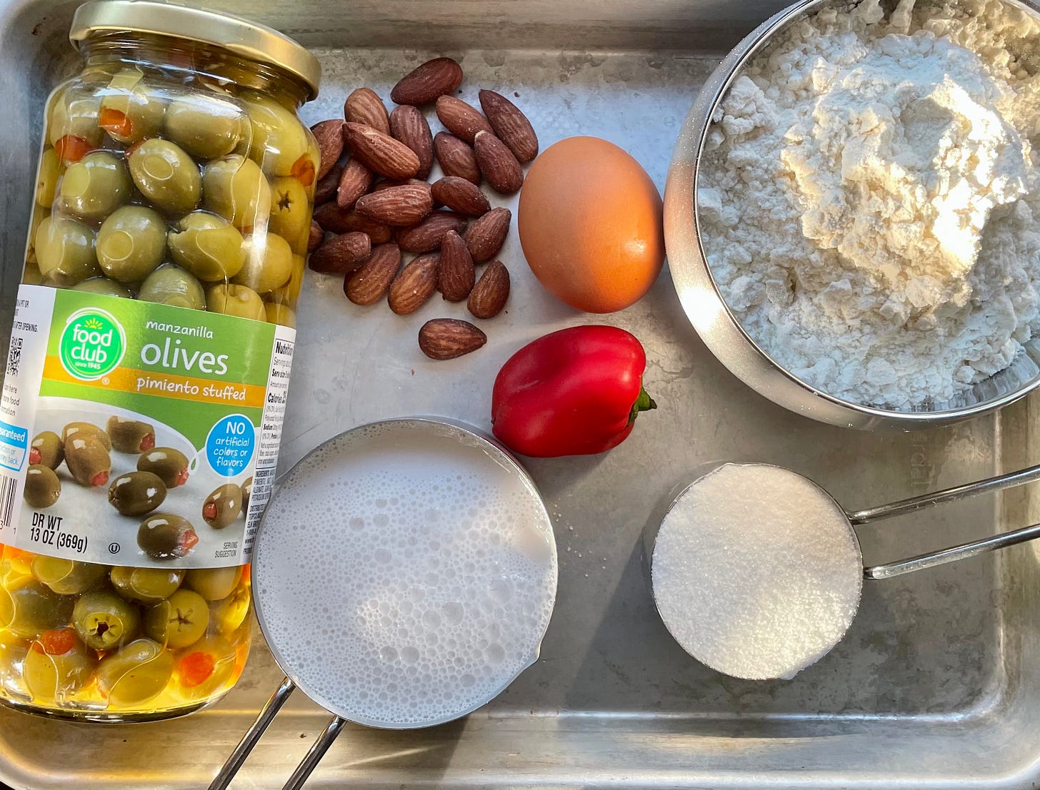 main ingredients for olive bread: pimento stuffed olives, nuts, milk, sugar, flour, egg, pimento, shown in morning light