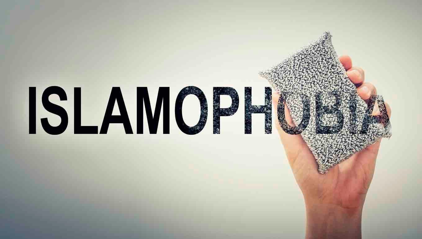 Hand erasing the word ISLAMOPHOBIA. Conceptual poster for rejecting islamophobia and racism.