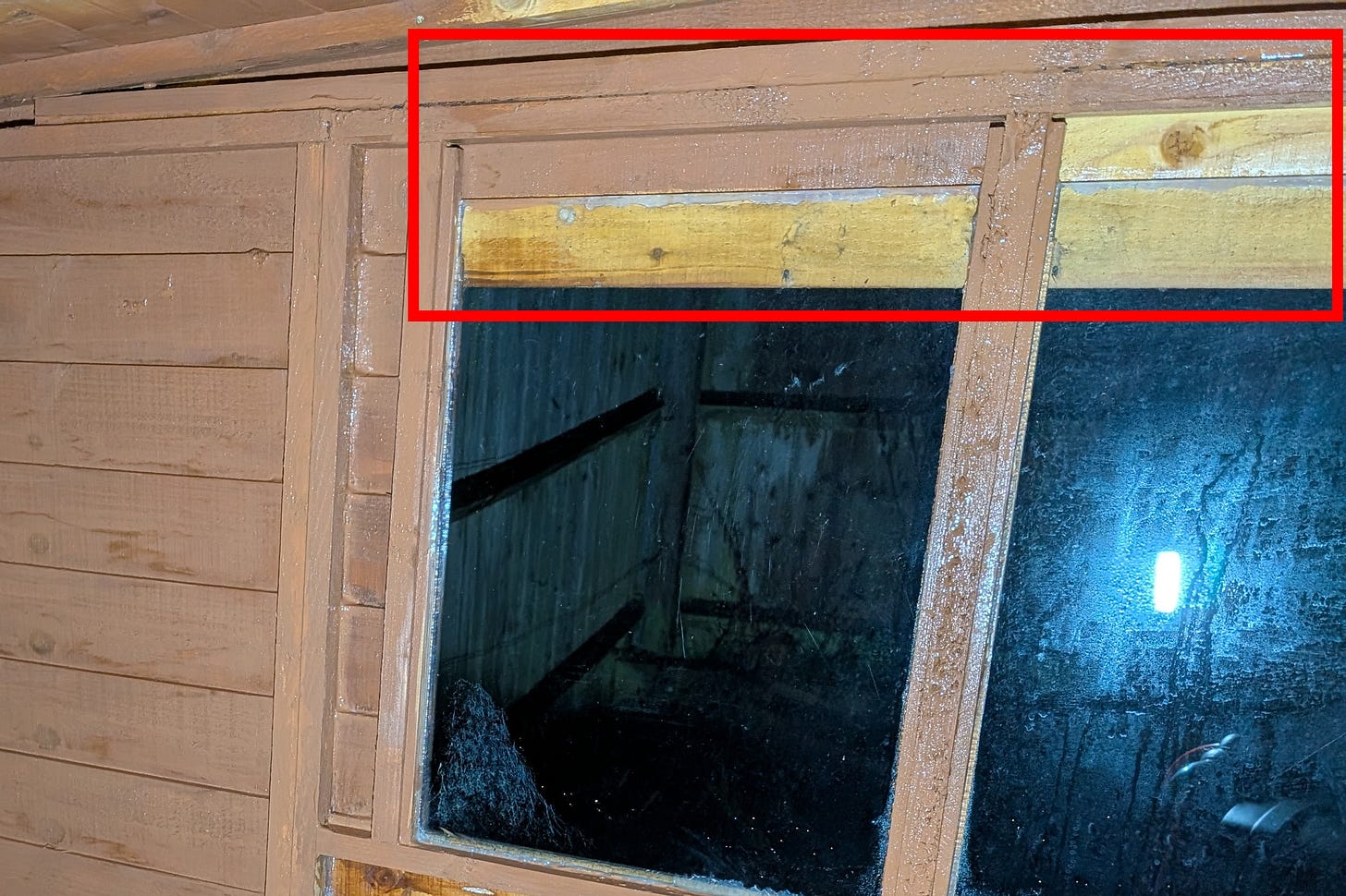 Annotated photo of a shed window frame, highlighting how the internal pane is larger than the exterior cut-out, creating a hidden ledge for storage.