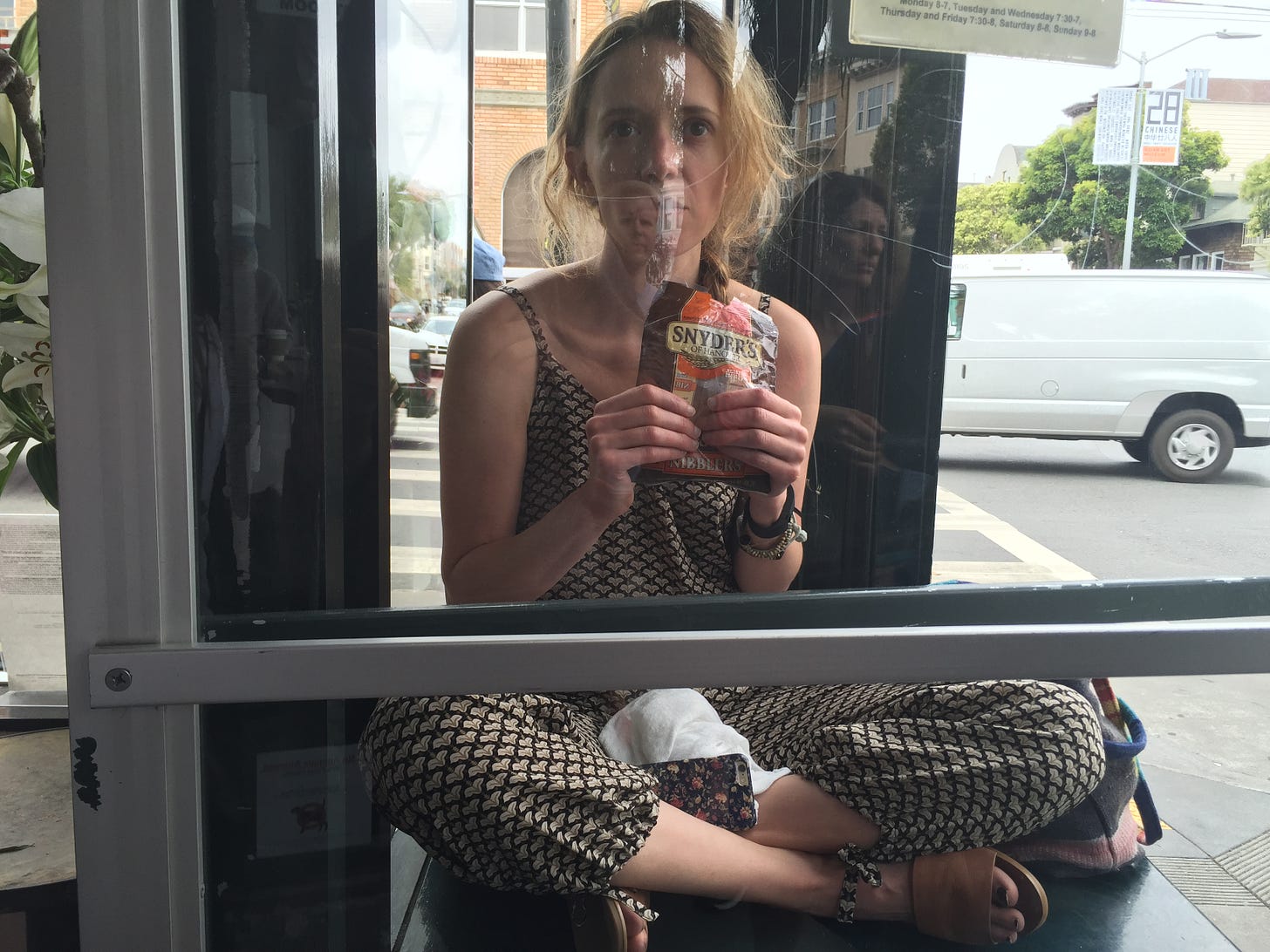I am sitting outside a window holding pretzels