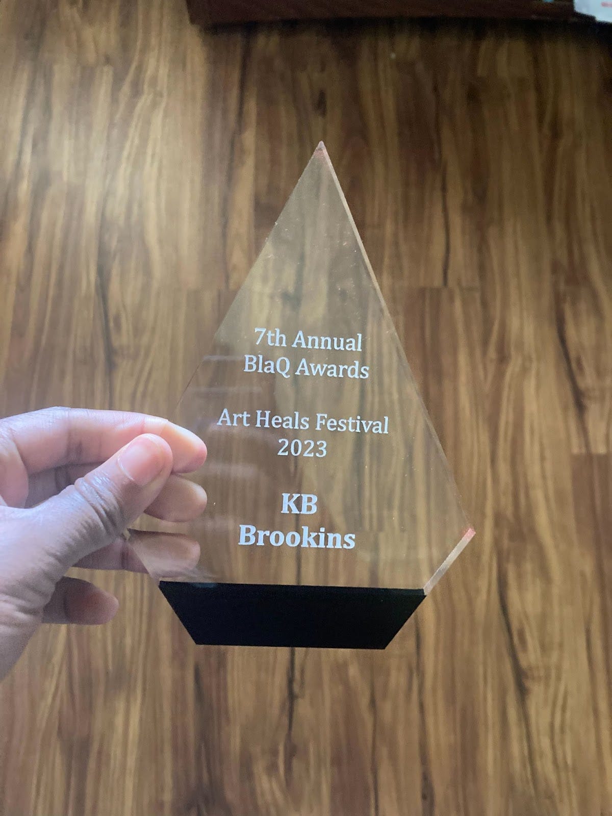 Picture of the award that KB recieved. It's holographic with "7th annual blaq awards" on it. 