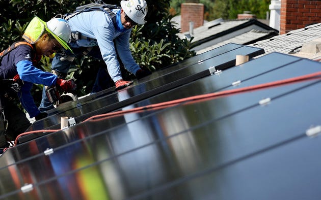 GRID Alternatives employees Tony Chang (L) and Sal Miranda install no-cost solar panels on the rooftop of a low-income household in Pomona, California.