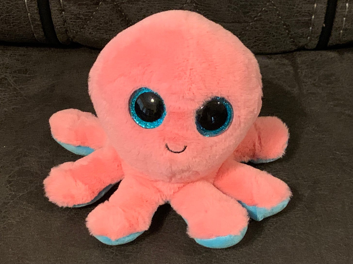 Smiling pink octopus stuffed animal with large blue eyes