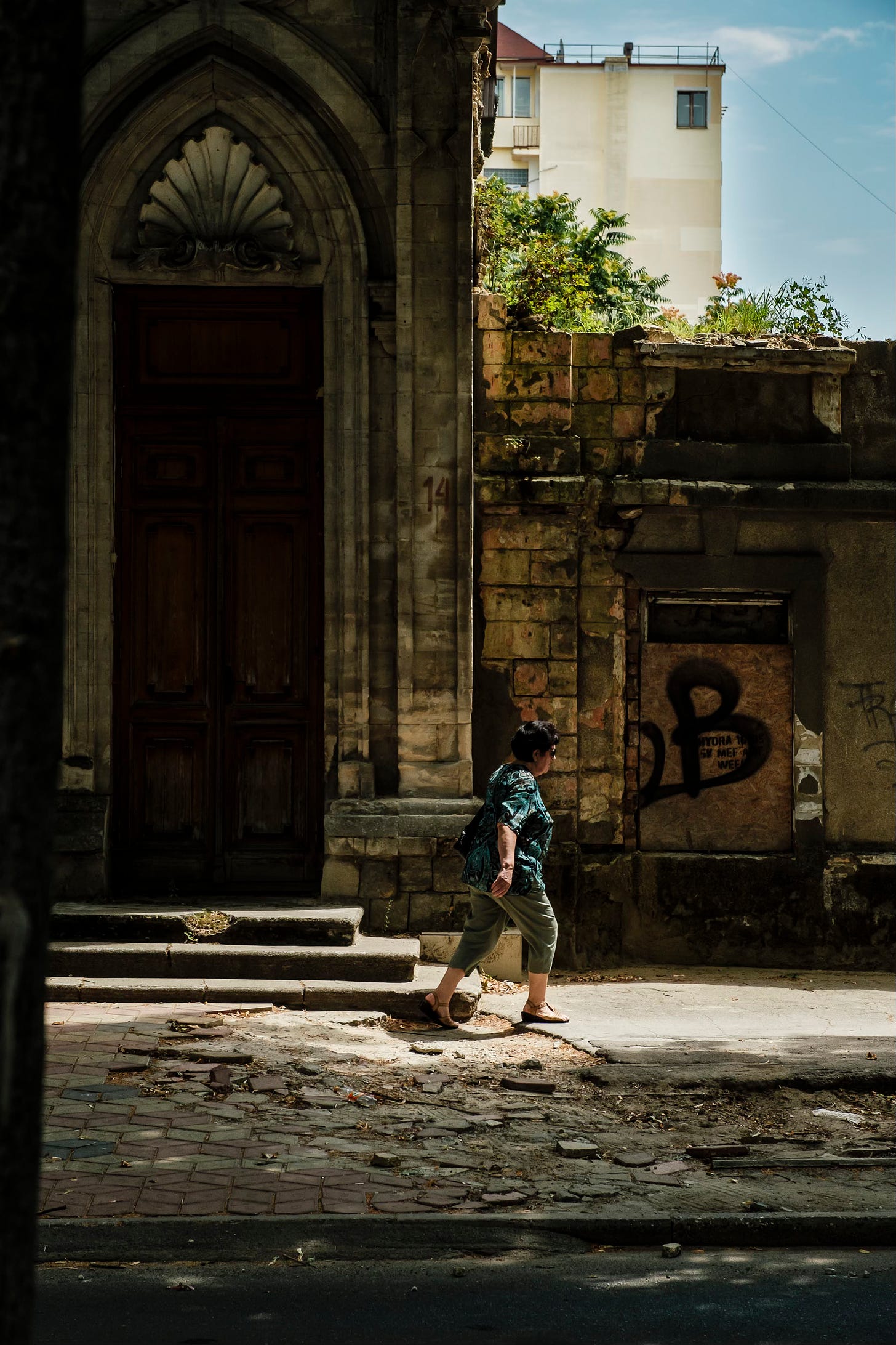 a woman passes by in front of a derelict building in Chisinau, Moldova