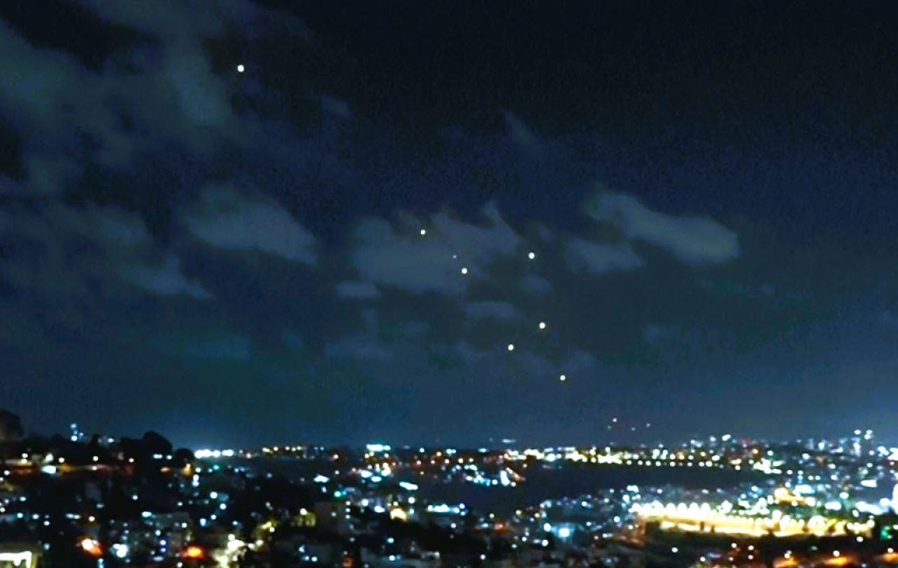 Dots of light, caused by missles, fall across a night sky above the city