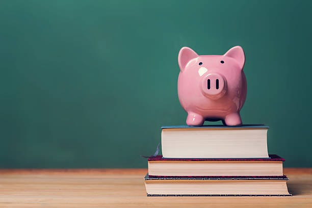 Piggy bank on top of books, cost of education theme Pink Piggy bank on top of books with chalkboard in the background as concept image of the costs of education finance books stock pictures, royalty-free photos & images