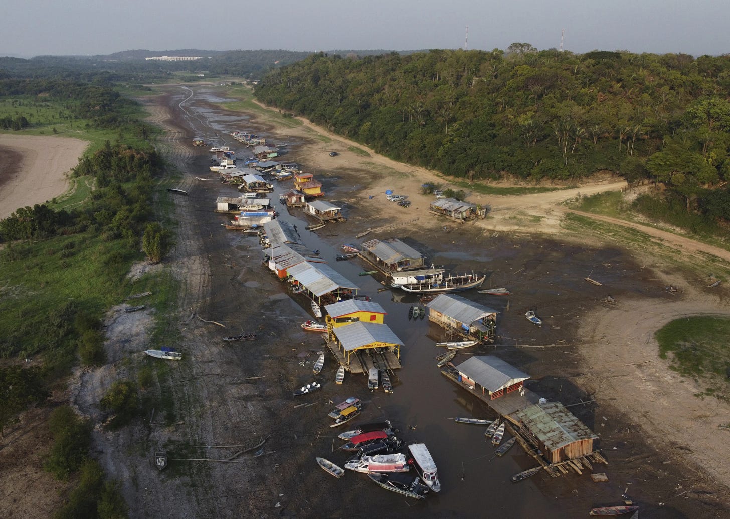 Floating homes and boats lay stranded on the dry bed of Puraquequara lake, amid a severe drought