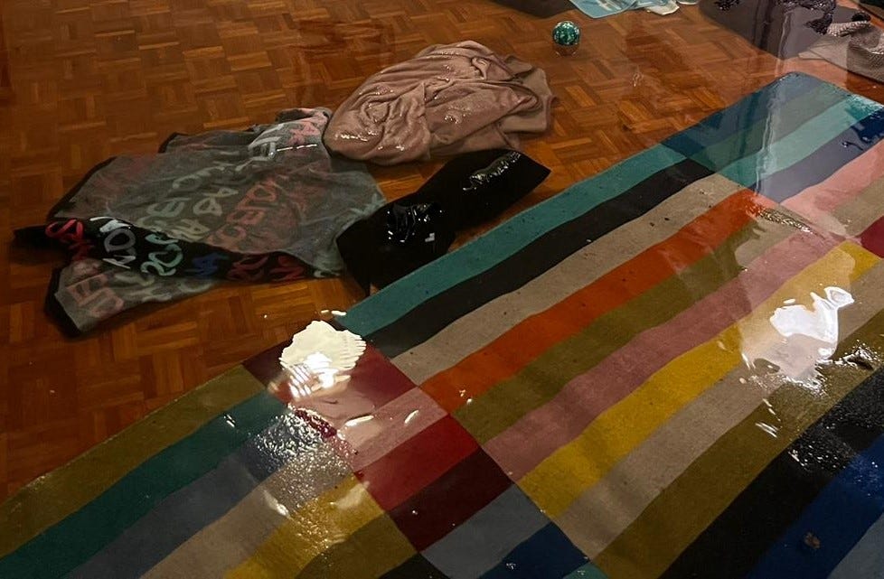 a living room floor submerged in two inches of water, towels and a rug floating on the surface