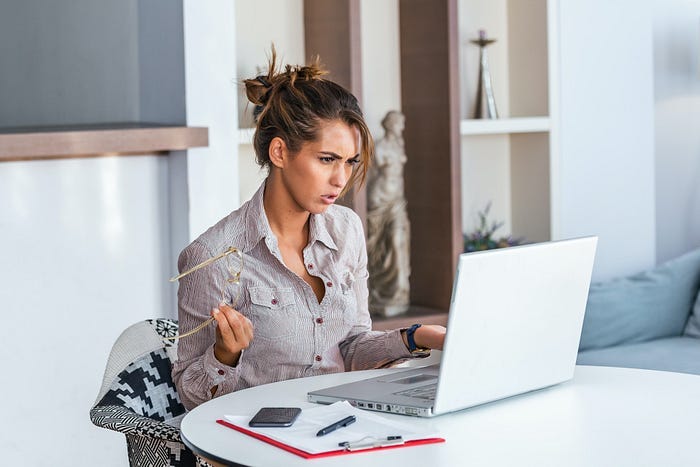 An angry-looking woman in front of a laptop. An angry-looking woman in front of a laptop.