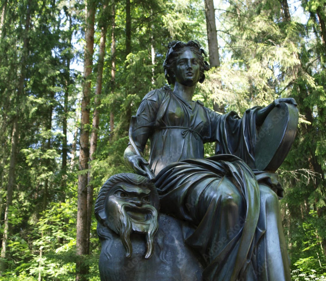 a bronze statue of the greek muse Thalia, surrounded by trees.