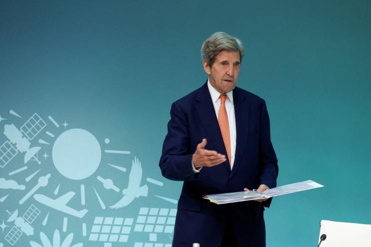 John Kerry speaking at a UN Climate Change Conference press conference in Dubai in a suit and tie.