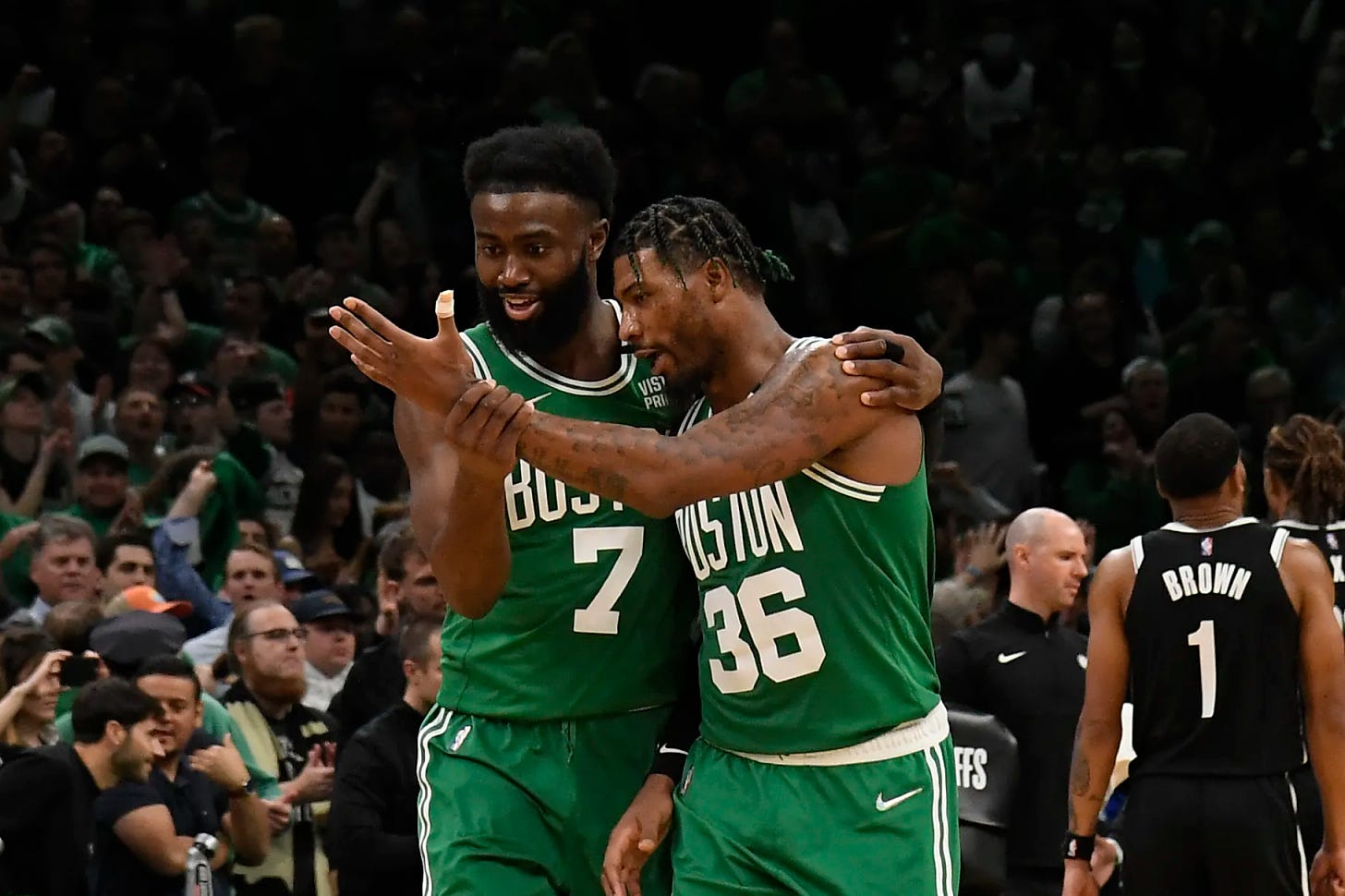 Marcus Smart staring at his left hand while Jaylen Brown also stares at his hand.