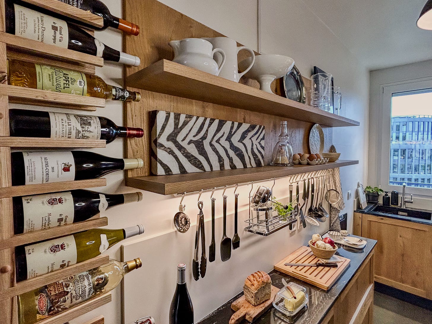 A small Paris kitchen wall with wine bottles, cooking utensils and decor