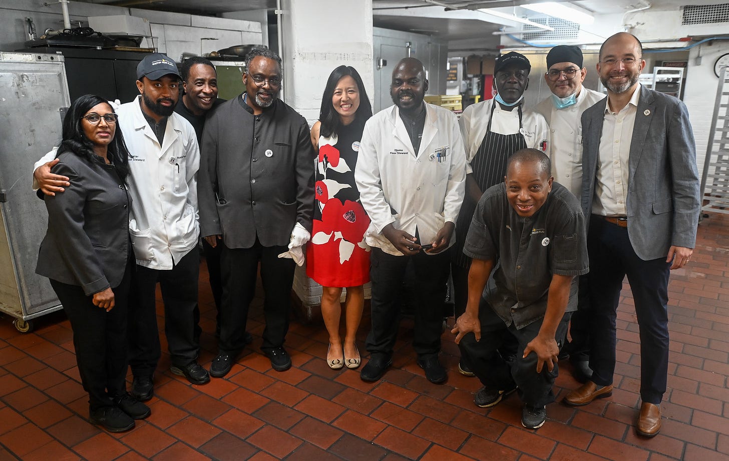 Michelle smiles for a photo with workers in the kitchen before the event