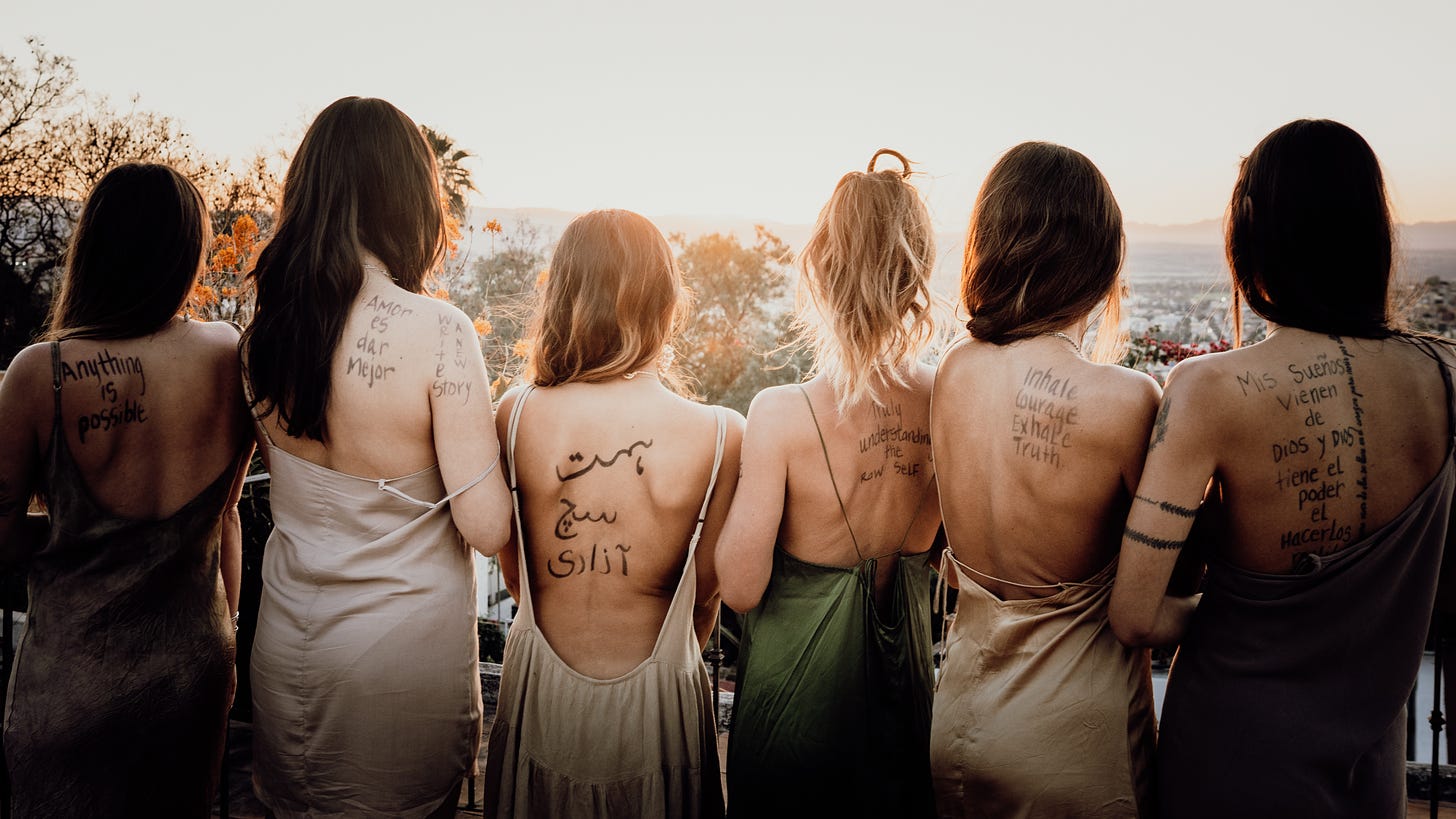 Women with their backs to the camera, showing written words on their skin