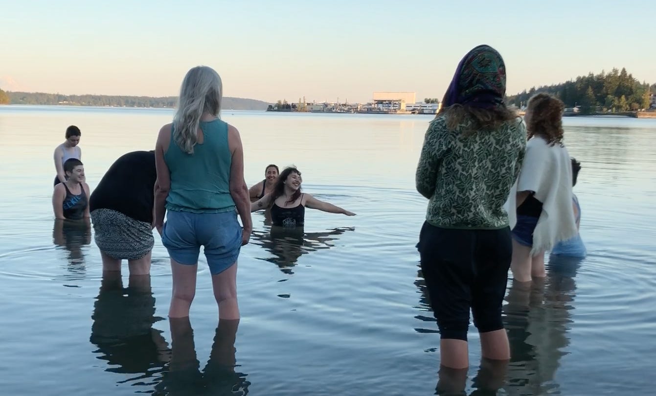 group of women singing while wading in the sea