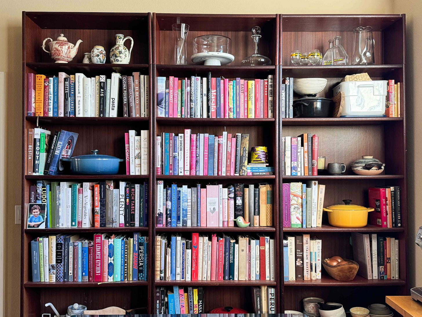 Cookbooks on a wall of wooden bookshelves.