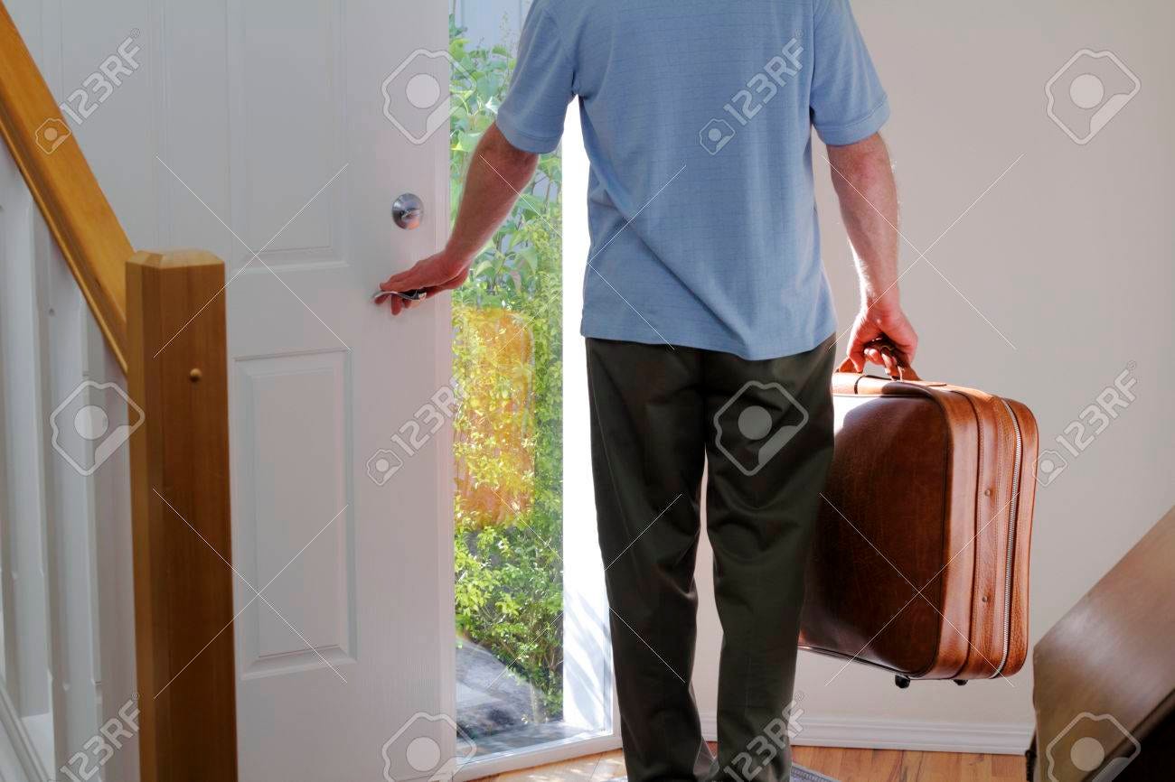A man carrying a suitcase about to walk out the front door of his house to travel  - 30626271