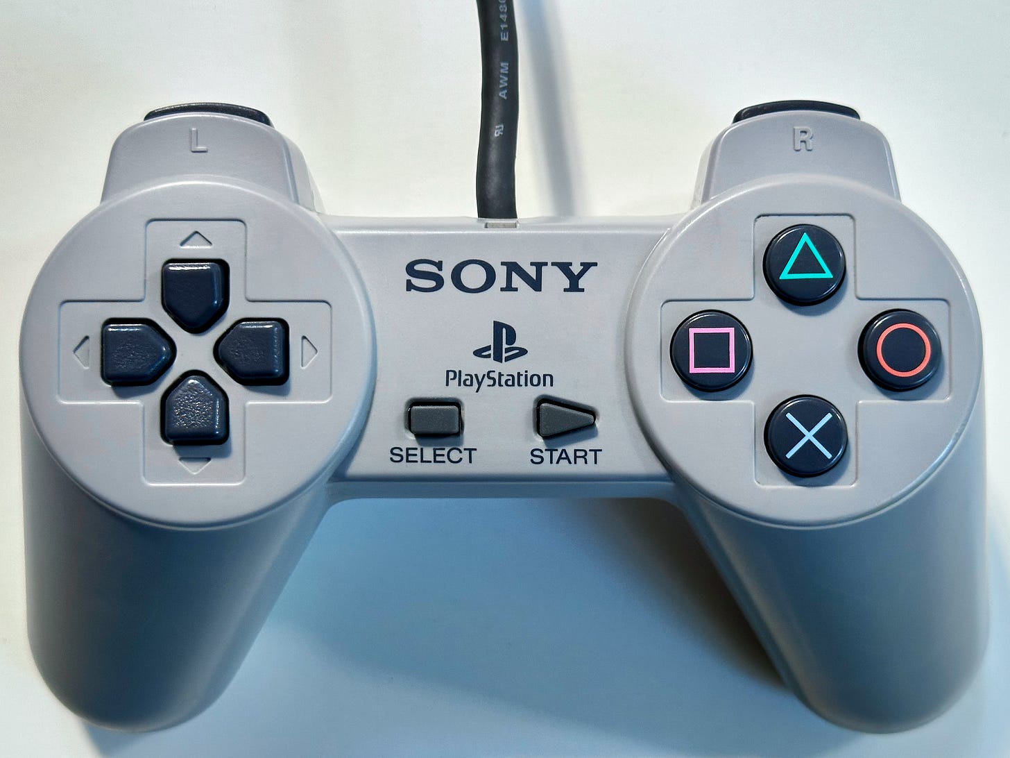 Photograph of the original PlayStation controller on a shadowy white background.