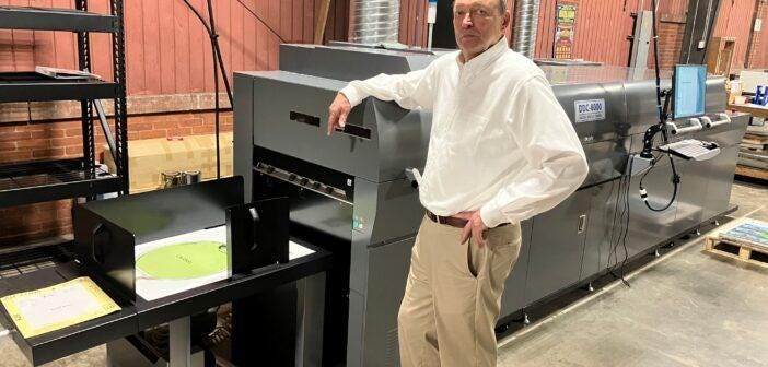 A person standing next to a large printer

Description automatically generated