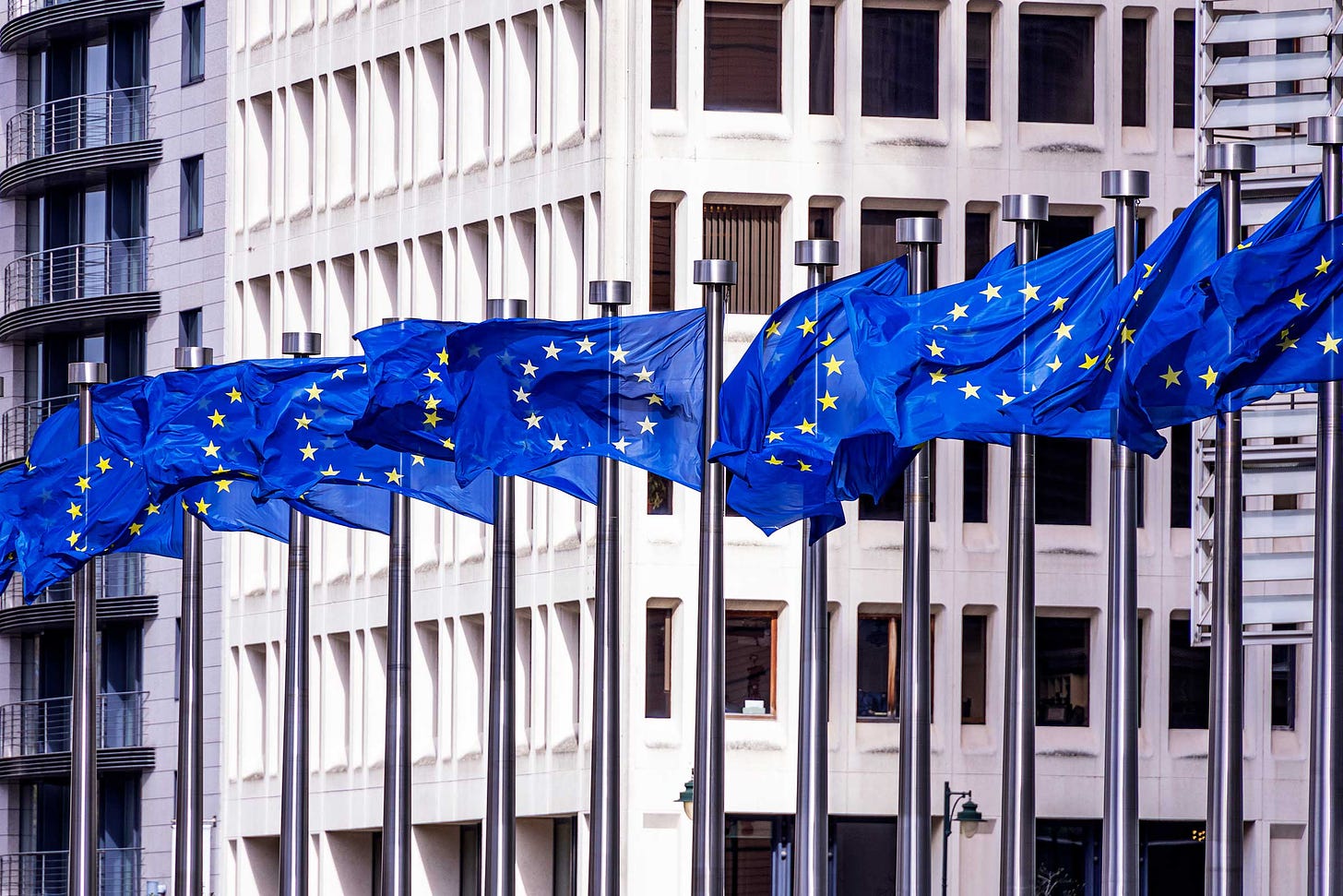 EU flags waving on poles outside of a building