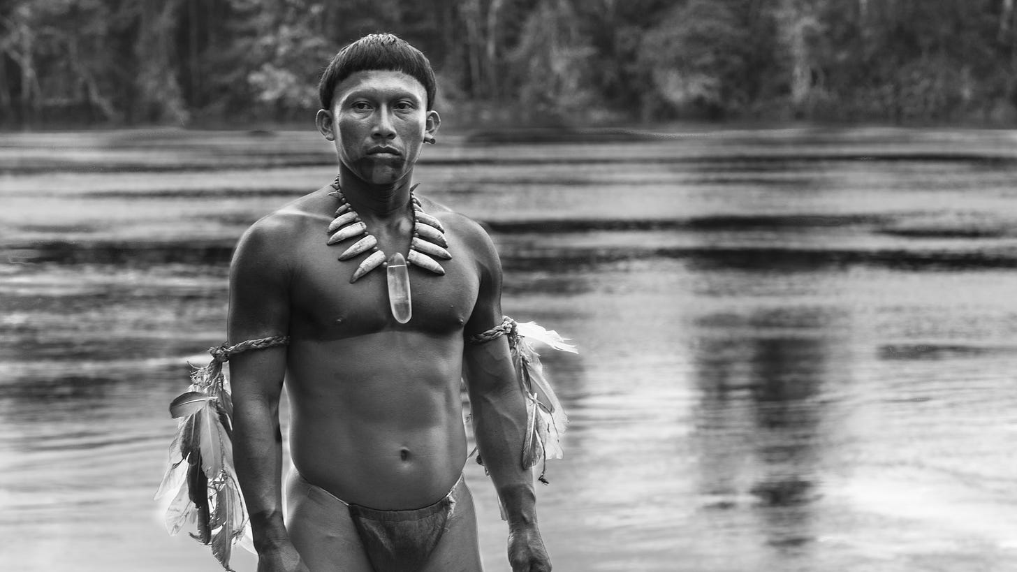 Movie still from Embrace the Serpent. An Amazonian shaman stands in front of a river.