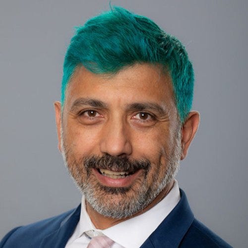 A photo of Dr Michele di Pietro in which they have died their hair teal green.