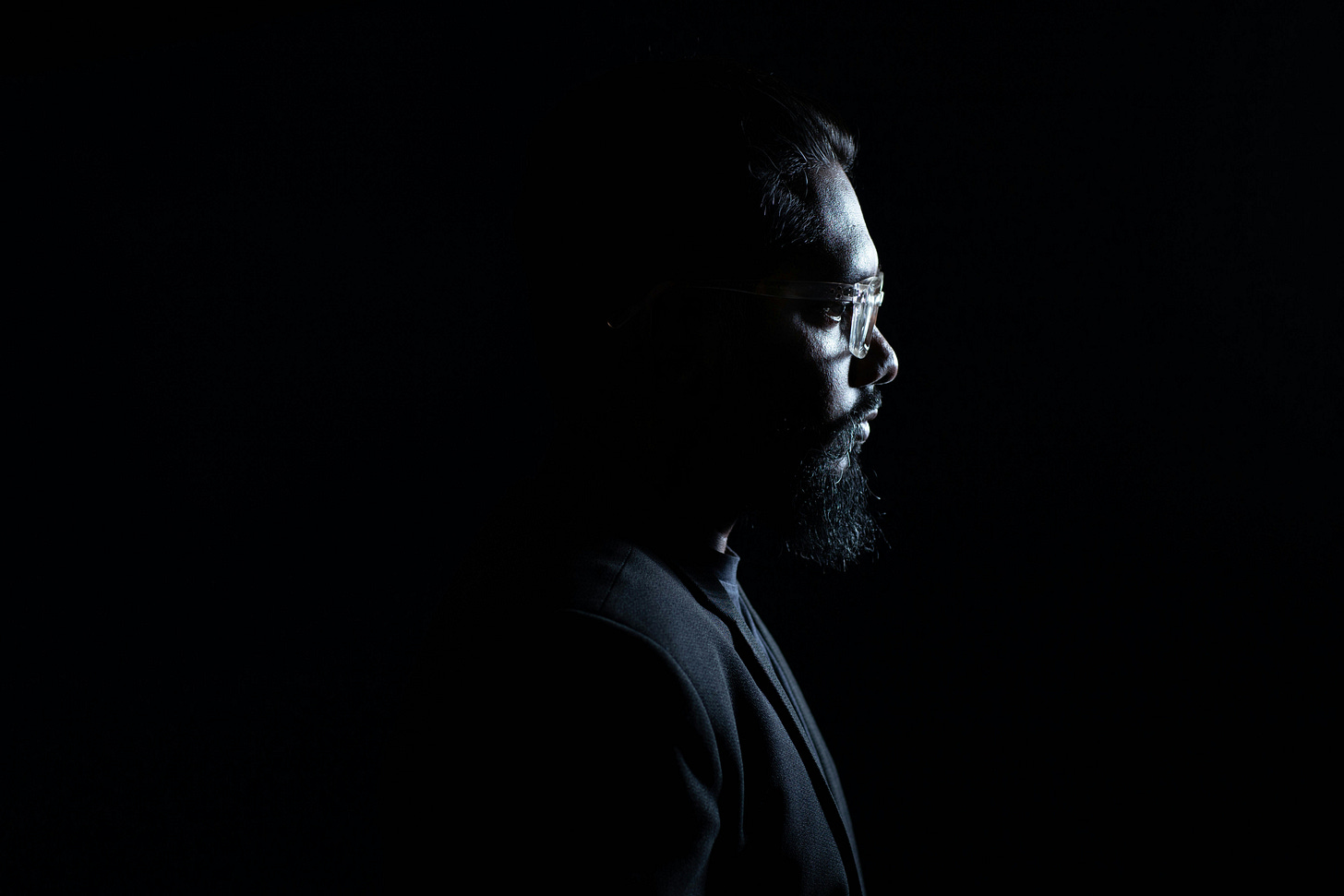 Side profile of a contemplative middle-aged man in a dark setting, symbolizing reflection on whether 50 is too old to start over in life or career.
