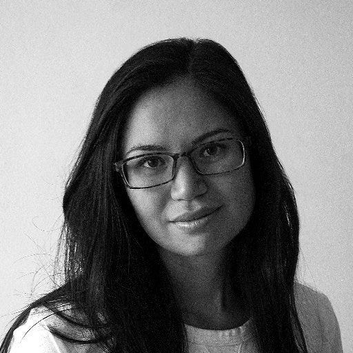 A woman with long black hair, glasses and a white shirt