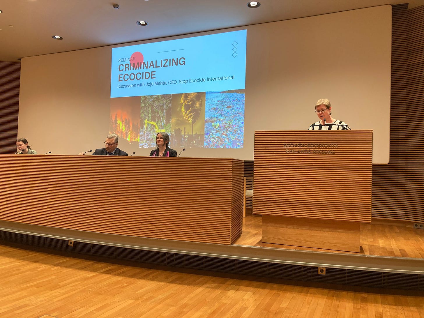 Jojo on a panel in parliament of Finland ('Criminalizing Ecocide' on screen in background)