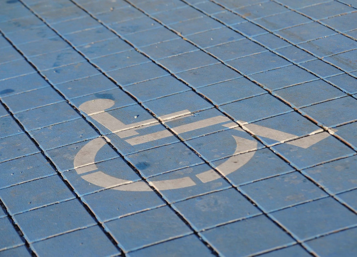 Wheelchair symbol painted on blue square paving stones