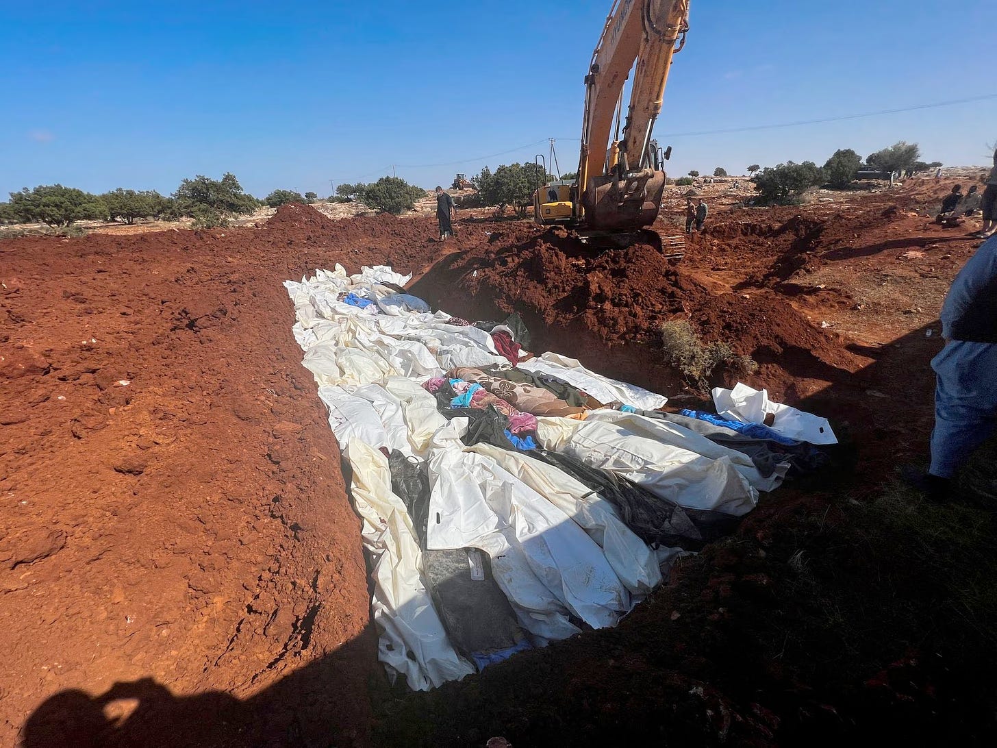 A backhoe rests over a freshly dug mass grave in Derna.