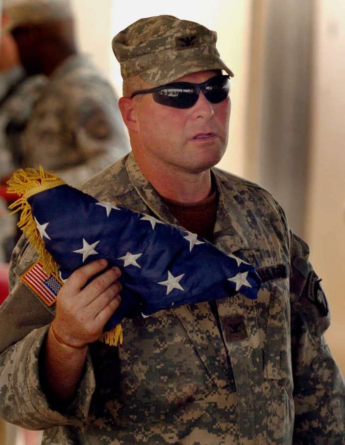 A person in a military uniform holding a flag

Description automatically generated with low confidence