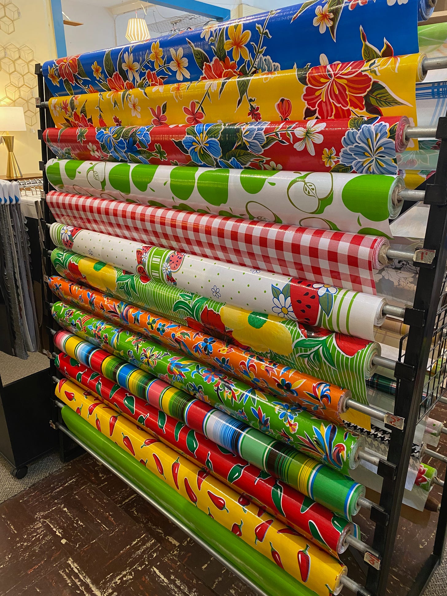 More than a dozen rolls of colorful oilcloth on a rack in a home furnishings store in Portland, Oregon. 