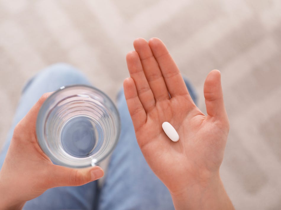 woman holding pill and glass of water