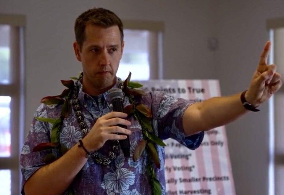 A person wearing a hawaiian shirt holding a microphone

Description automatically generated